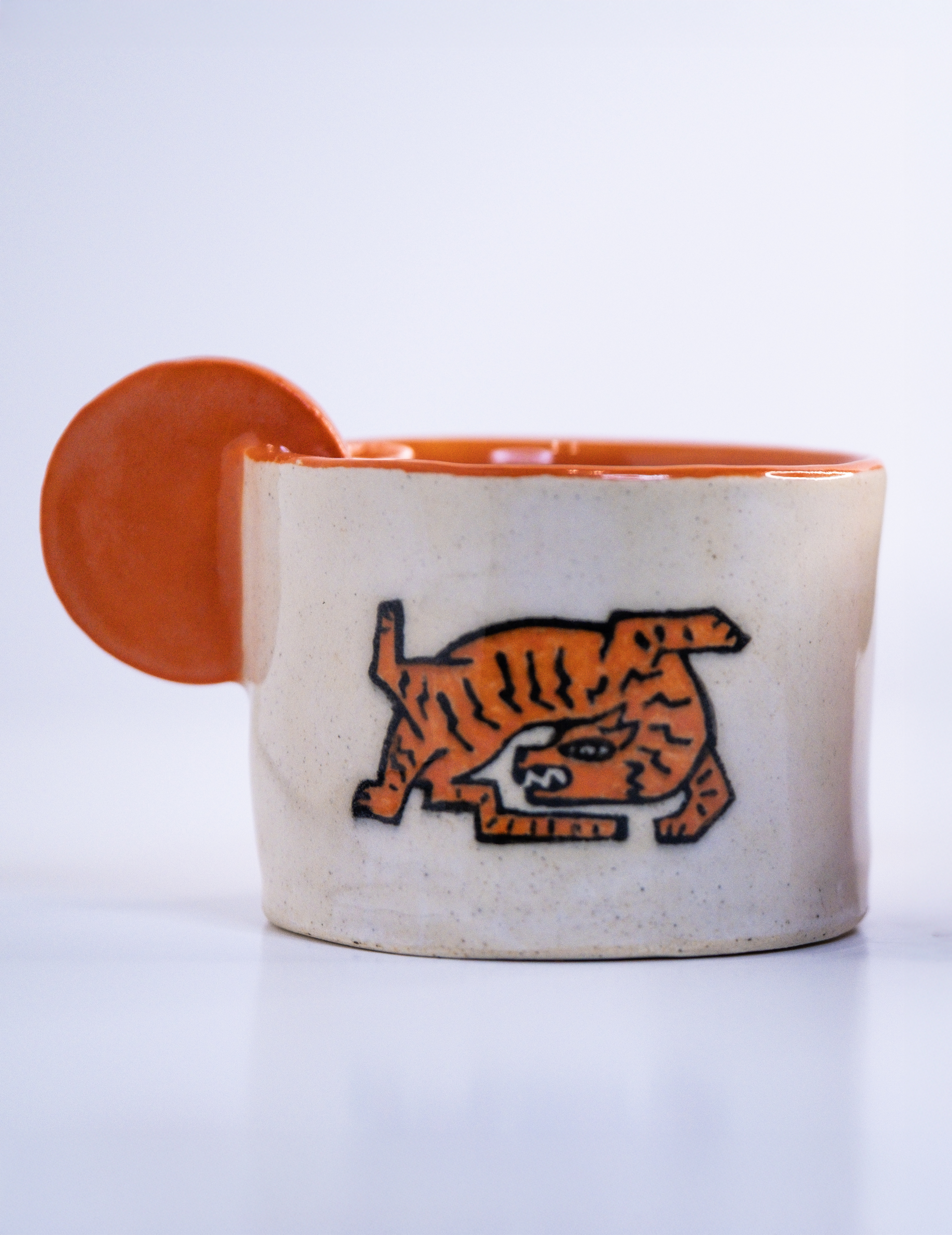 White ceramic tiger mug with an orange interior and circular handle