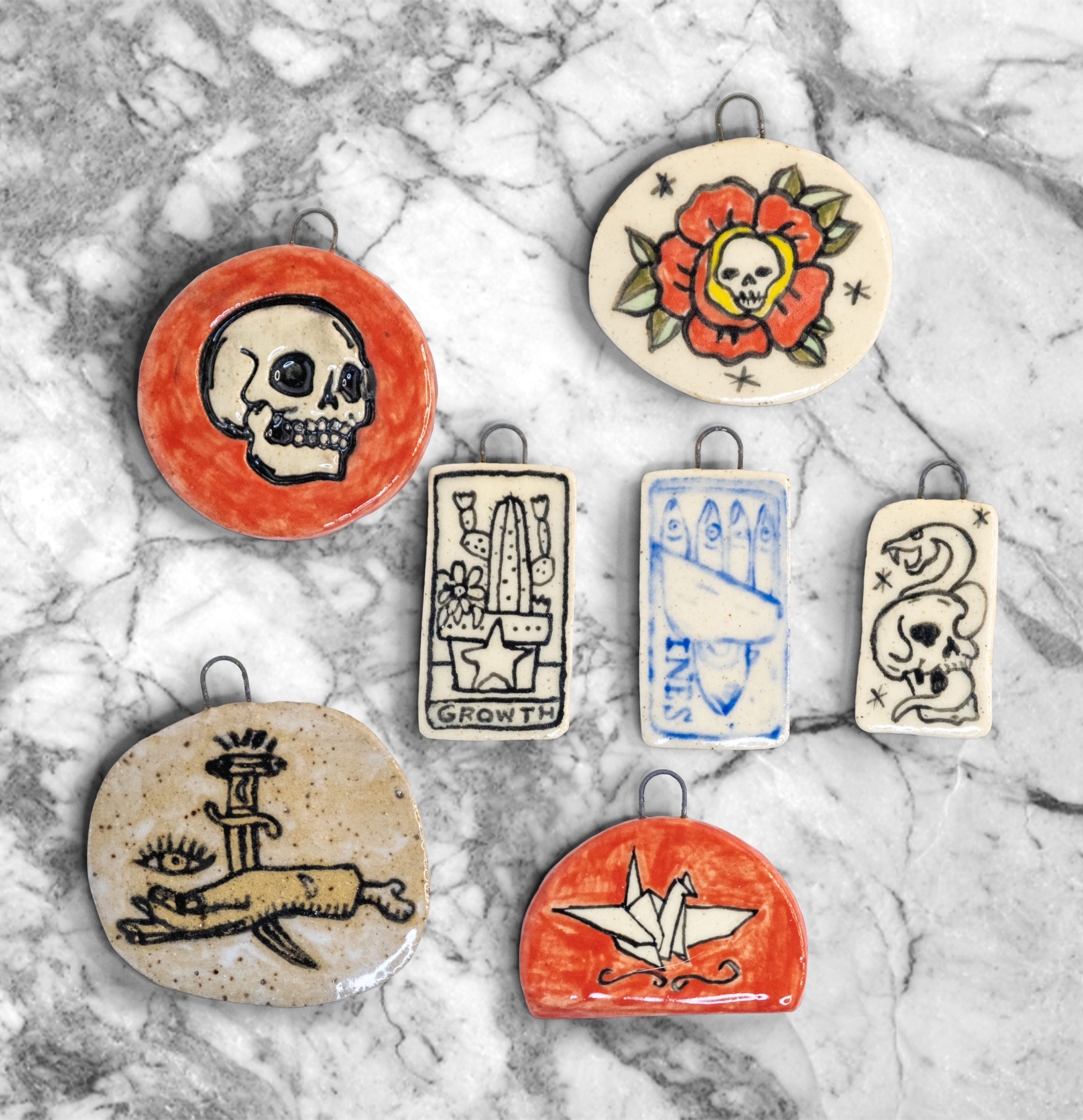Handmade illustrated charms featuring a skull, rose, horse, and other original artwork